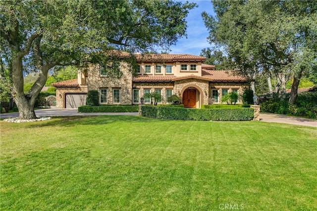 mediterranean / spanish home featuring a garage and a front lawn