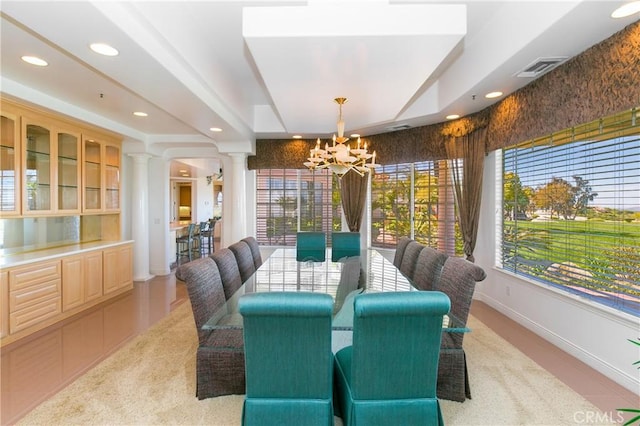 dining room with a healthy amount of sunlight, ornate columns, and an inviting chandelier