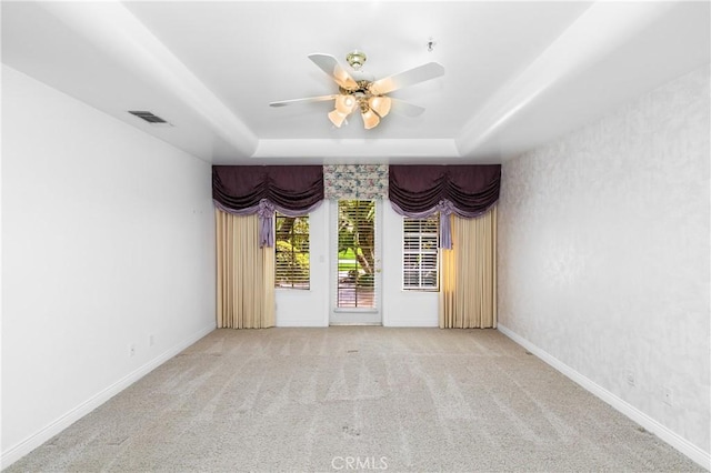 carpeted spare room featuring ceiling fan and a tray ceiling