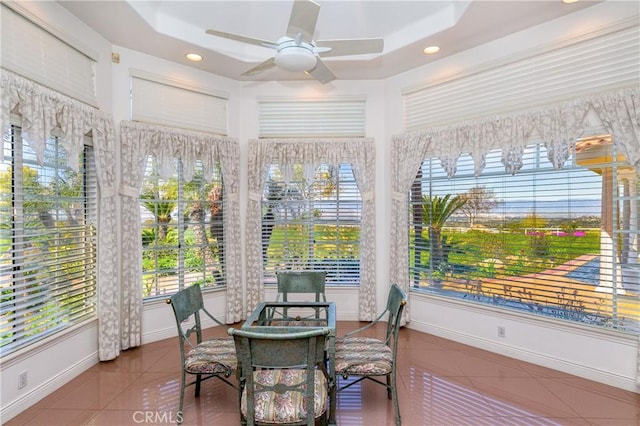 sunroom / solarium with ceiling fan and a tray ceiling