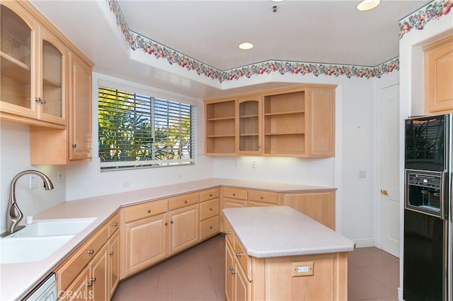 kitchen with black refrigerator with ice dispenser, light brown cabinetry, a center island, and sink