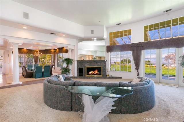 carpeted living room featuring french doors, a fireplace, a high ceiling, and a chandelier