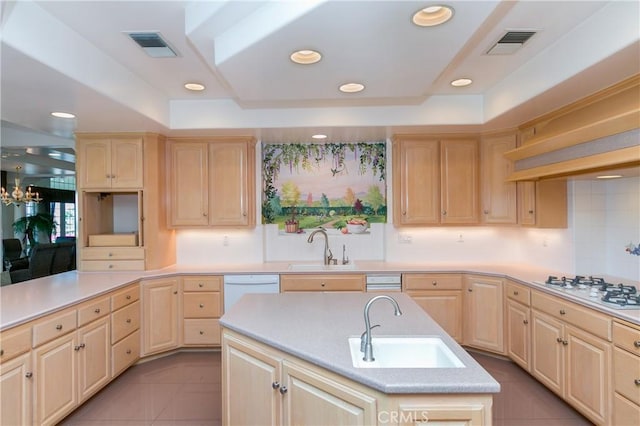 kitchen featuring white appliances, an island with sink, light brown cabinets, and sink