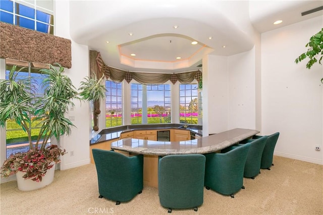 dining room featuring a raised ceiling, light colored carpet, sink, and wine cooler