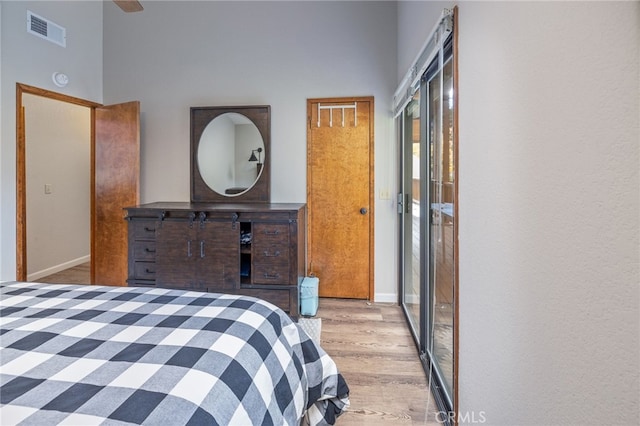 bedroom featuring a towering ceiling and light hardwood / wood-style flooring