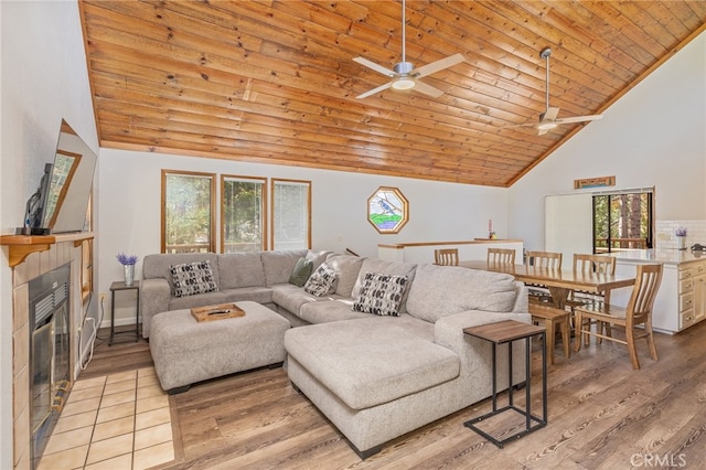 living room with wood ceiling, a tiled fireplace, light hardwood / wood-style floors, and high vaulted ceiling