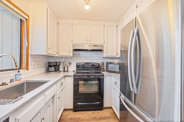 kitchen with sink, stainless steel fridge, white cabinetry, backsplash, and black range with electric cooktop