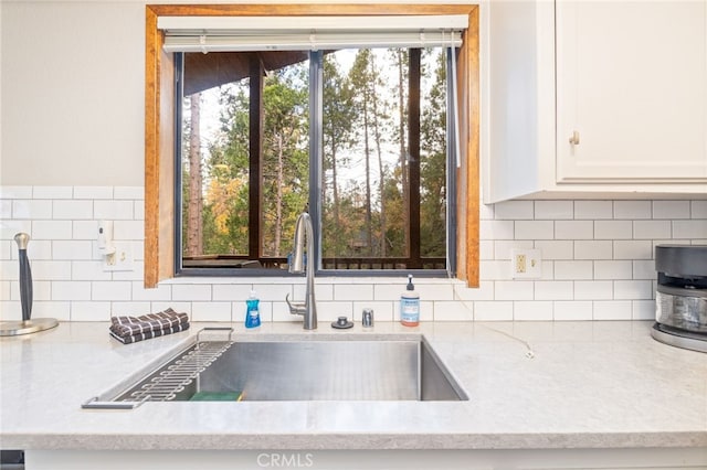 kitchen featuring tasteful backsplash, white cabinetry, sink, and light stone counters