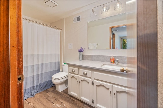 bathroom featuring wood-type flooring, walk in shower, vanity, and toilet