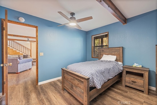 bedroom featuring beam ceiling, hardwood / wood-style flooring, and ceiling fan