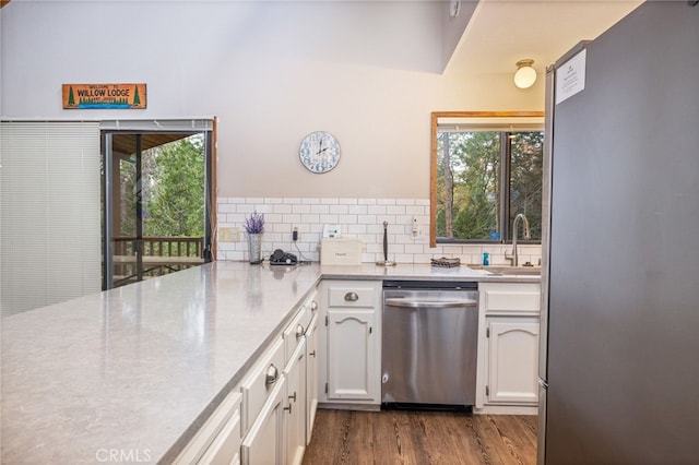 kitchen featuring sink, white cabinetry, stainless steel appliances, decorative backsplash, and light wood-type flooring