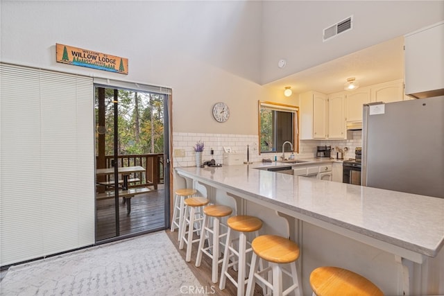 kitchen with electric range oven, decorative backsplash, and kitchen peninsula