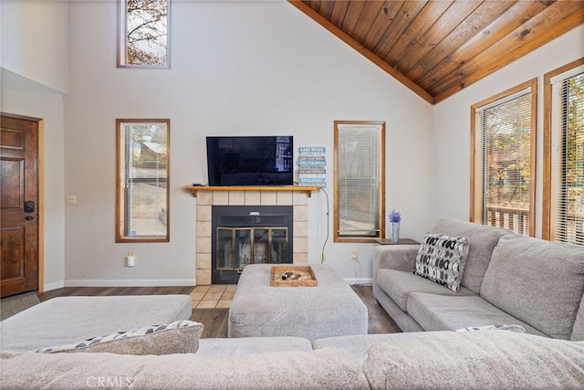 living room with wood ceiling, a tiled fireplace, high vaulted ceiling, and light wood-type flooring