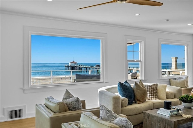 living room featuring a water view, wood-type flooring, crown molding, and a view of the beach