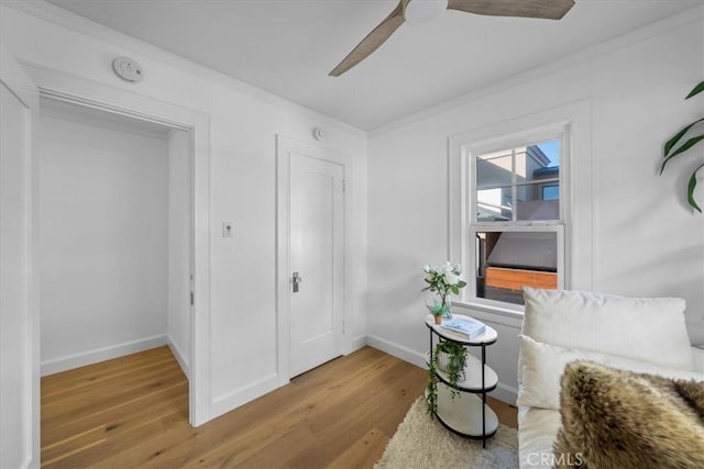 sitting room with crown molding, ceiling fan, and wood-type flooring