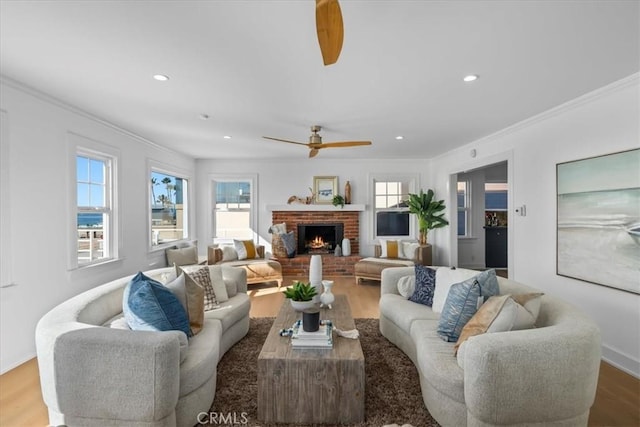 living room featuring a fireplace, hardwood / wood-style flooring, ceiling fan, and crown molding