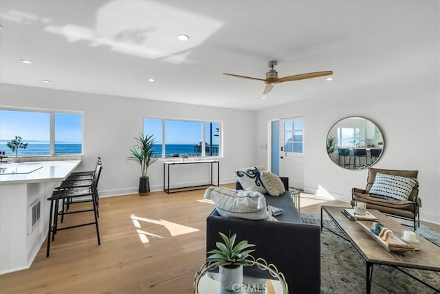 living room with a water view, light hardwood / wood-style flooring, and a wealth of natural light