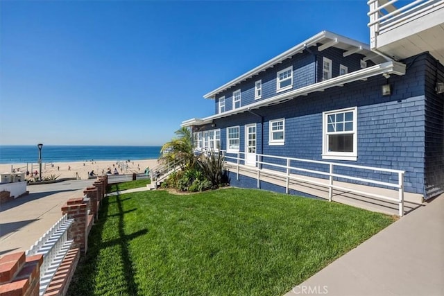 view of home's exterior with a lawn, a water view, and a view of the beach