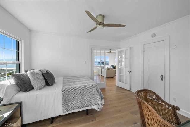 bedroom featuring ceiling fan, french doors, ornamental molding, and light wood-type flooring