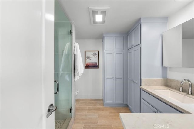 bathroom with wood-type flooring, vanity, toilet, and a shower with door