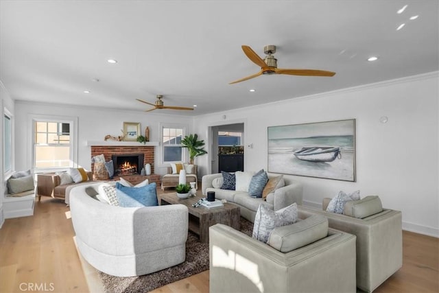 living room with light hardwood / wood-style floors, a brick fireplace, ceiling fan, and ornamental molding