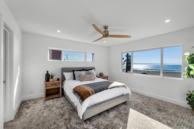 carpeted bedroom with multiple windows, a water view, and ceiling fan