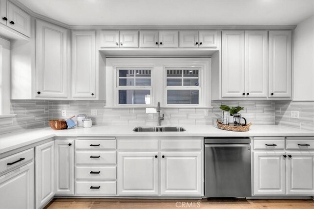 kitchen with backsplash, sink, white cabinets, and stainless steel dishwasher