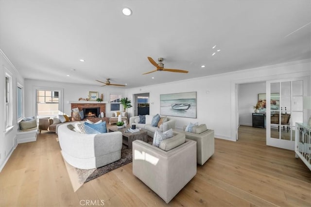 living room featuring french doors, light hardwood / wood-style floors, a brick fireplace, and ornamental molding