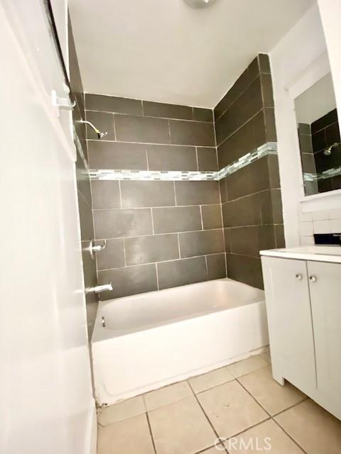 bathroom with tiled shower / bath, tile patterned floors, and vanity