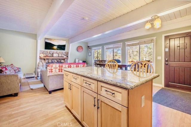 kitchen featuring light stone countertops, a kitchen island, light brown cabinetry, beamed ceiling, and light wood-type flooring