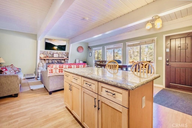 kitchen with open floor plan, light wood-type flooring, light stone counters, and beam ceiling