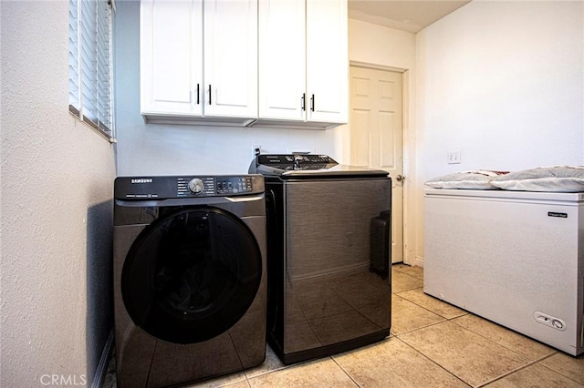 laundry area featuring washer and dryer, cabinets, and light tile patterned floors