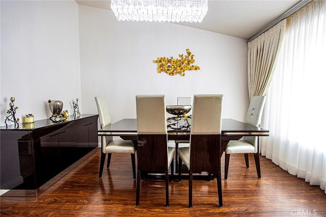 dining room with dark wood-type flooring, a chandelier, and vaulted ceiling