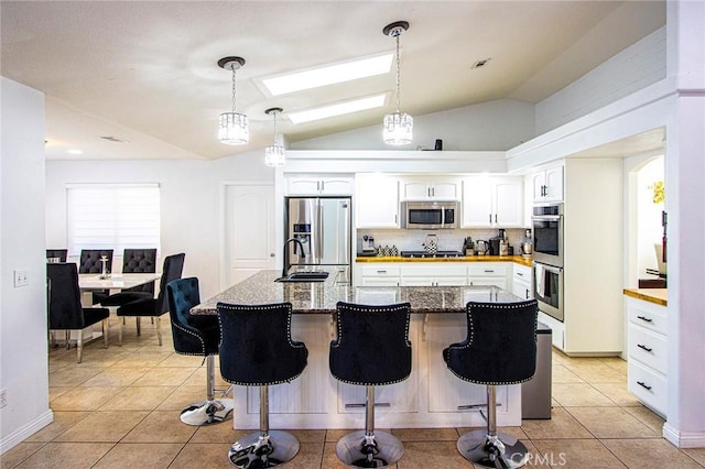 kitchen with light tile patterned floors, white cabinets, stainless steel appliances, and vaulted ceiling