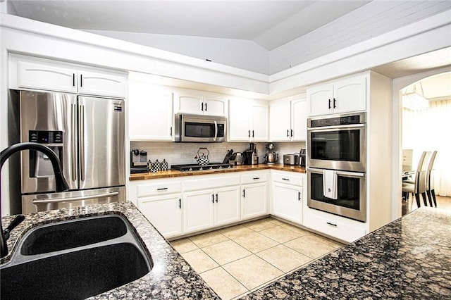 kitchen with white cabinets, appliances with stainless steel finishes, vaulted ceiling, and light tile patterned flooring