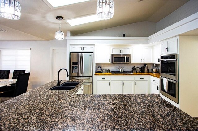 kitchen with white cabinetry, sink, pendant lighting, lofted ceiling, and appliances with stainless steel finishes