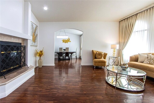 living room with lofted ceiling, dark wood-type flooring, and a tiled fireplace