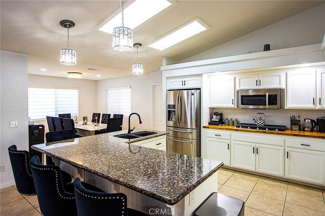 kitchen featuring decorative light fixtures, white cabinetry, a kitchen island with sink, and appliances with stainless steel finishes