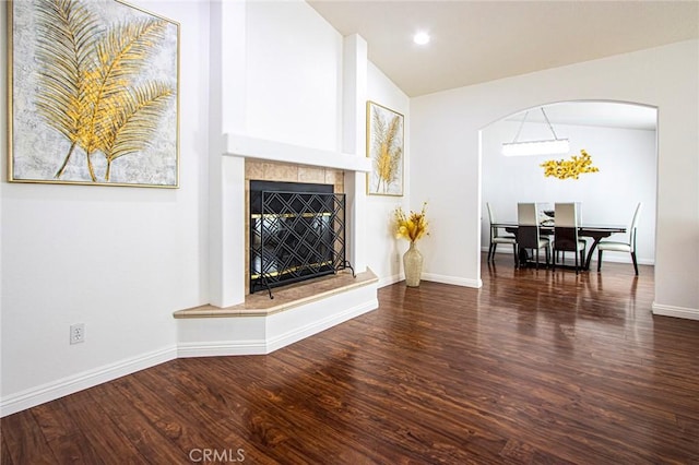 living room featuring a tiled fireplace, lofted ceiling, and dark hardwood / wood-style floors