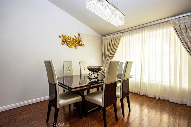 dining space with dark hardwood / wood-style floors, an inviting chandelier, and lofted ceiling