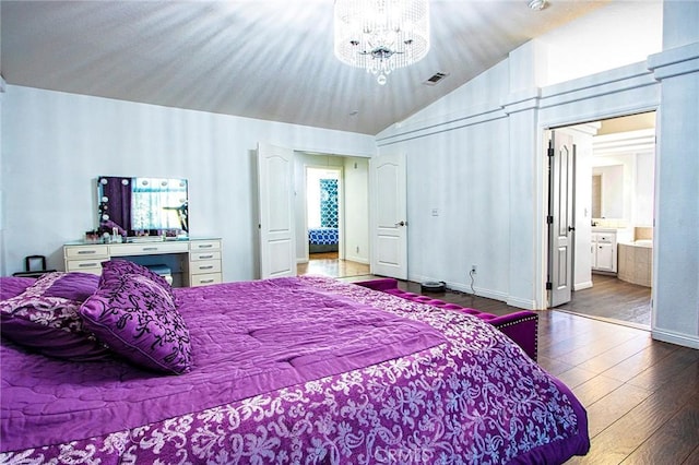 bedroom featuring connected bathroom, hardwood / wood-style floors, a chandelier, and lofted ceiling