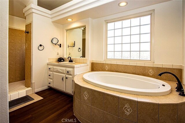 bathroom with vanity, a wealth of natural light, hardwood / wood-style floors, and plus walk in shower