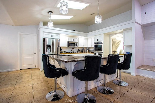 kitchen with a breakfast bar, stainless steel appliances, sink, white cabinets, and lofted ceiling