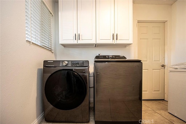 laundry room with separate washer and dryer, light tile patterned floors, and cabinets