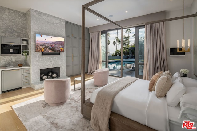 bedroom featuring access to outside, light hardwood / wood-style flooring, and a fireplace