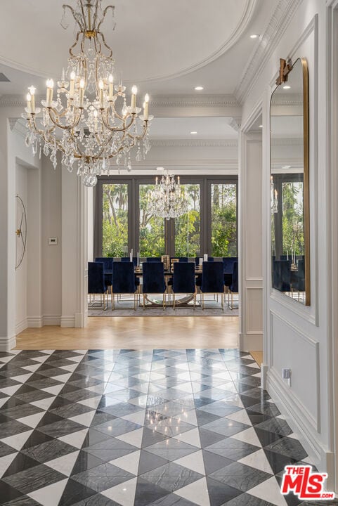 unfurnished dining area featuring french doors, crown molding, a wealth of natural light, and a chandelier