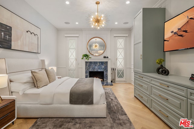 bedroom with ornamental molding, a notable chandelier, a fireplace, and light parquet floors