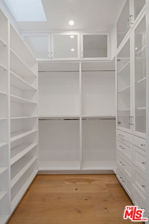 spacious closet featuring light hardwood / wood-style floors and a skylight