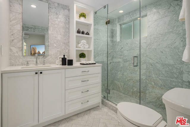 bathroom with toilet, a shower with shower door, vanity, and tile walls