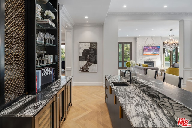 interior space with sink, a high end fireplace, light parquet floors, dark stone countertops, and ornamental molding